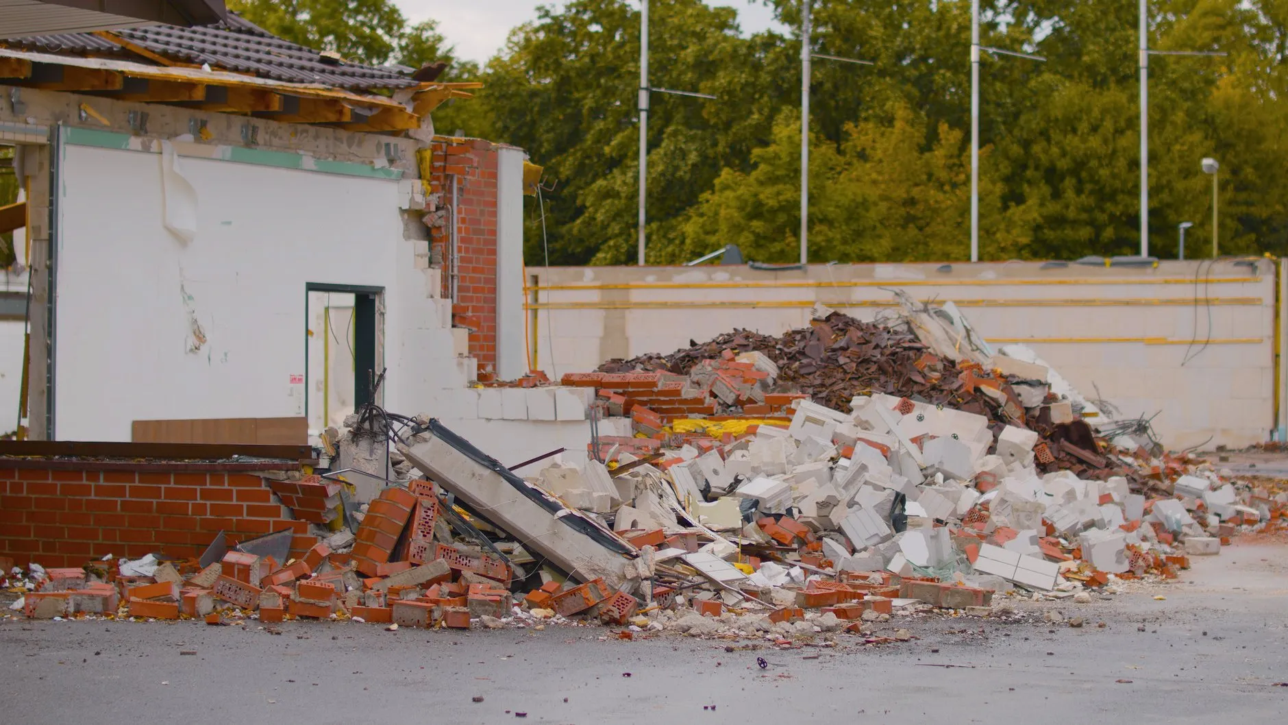 A single-storey building part demolished, with brick and block rubble heaped in front