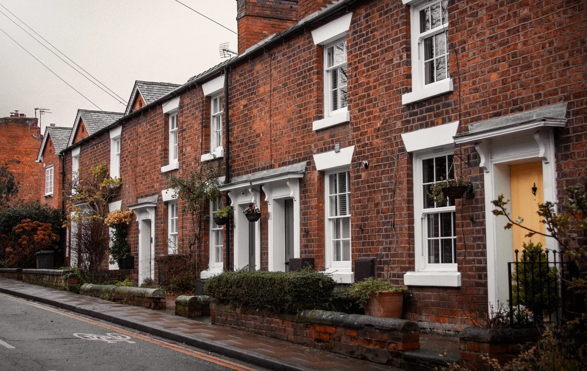 A row of red-brick terraced houses fronting straight onto a narrow street with no driveways